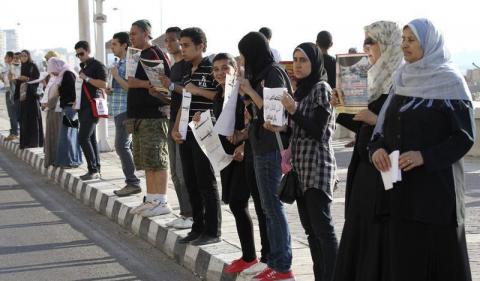 Demonstrators stand in silence on the second anniversary of the death of Egyptian Khaled Said as they carry his photo in front his house in the port city of Alexandria