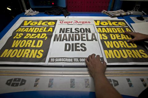 Newspaper posters announcing the death of former South African President Nelson Mandela are displayed at a printing press in the early hours of the morning in Cape Town