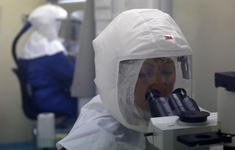 A doctor uses a microscope to look at virus samples in a Biosafety Level III laboratory at the National Institute of Health in Lima