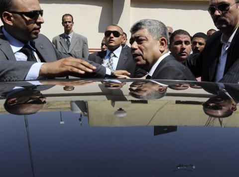 Egypt's Interior Minister Mohamed Ibrahim (C) gets into his car after attending the funerals of policemen killed during yesterday's clashes in Cairo