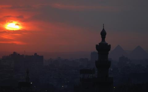 The sun sets on the minarets and the Great Pyramids of Giza (R) in Old Cairo