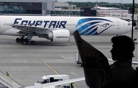 A passenger reads a newspaper at a departure hall of London's Heathrow terminal as an EgyptAir plane taxis on the tarmac of the airport, May 20, 2016. PHOTO BY REUTERS/Yannis Behrakis