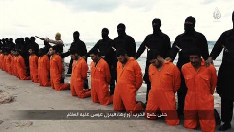 Men in orange jumpsuits purported to be Egyptian Christians held captive by the Islamic State (IS) kneel in front of armed men along a beach said to be near Tripoli, in this still image from an undated video made available on social media on February 15, 2015. PHOTO BY REUTERS/Social media via Reuters TV