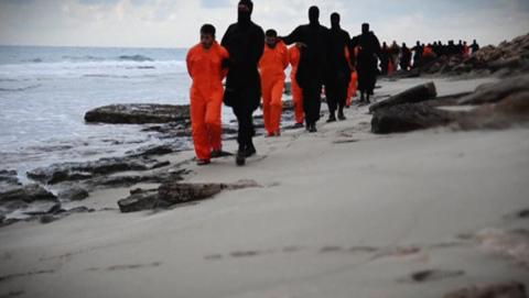 Men in orange jumpsuits purported to be Egyptian Christians held captive by the Islamic State (IS) are marched by armed men along a beach said to be near Tripoli, in this still image from an undated video made available on social media on February 15, 2015. PHOTO BY REUTERS/Social media via Reuters TV