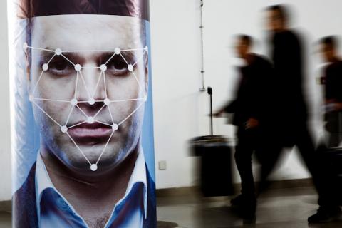 People walk past a poster simulating facial recognition software at the Security China 2018 exhibition on public safety and security in Beijing, China, October 24, 2018. PHOTO BY REUTERS/Thomas Peter