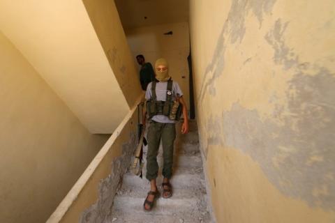 A Nusra Front fighter walks with his weapon inside a building in the Sheikh Maksoud neighbourhood of Aleppo, Syria, August 3, 2015. PHOTO BY REUTERS/Abdalrhman Ismail