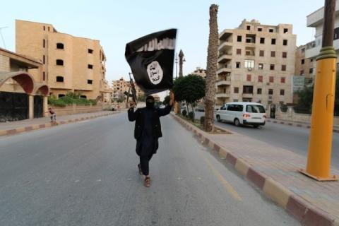 A member loyal to the Islamic State in Iraq and the Levant (ISIL) waves an ISIL flag in Raqqa, June 29, 2014. PHOTO BY REUTERS/Stringer