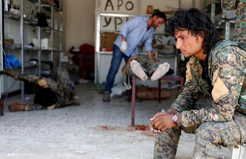 A Syrian Democratic Forces (SDF) fighter sit as medics treat his comrades injured by sniper fired by Islamic State militants in a field hospital in Raqqa, Syria, June 28, 2017. PHOTO BY REUTERS/Goran Tomasevic