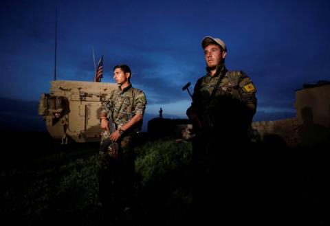 Kurdish fighters from the People's Protection Units (YPG) stand near a U.S military vehicle in the town of Darbasiya near the Turkish border, Syria, April 28, 2017. PHOTO BY REUTERS/Rodi Said