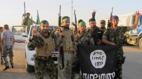 Shi'ite fighters pose with a black flag belonging to the Islamic State, which they pulled down after capturing the town of Jurf al-Sakhar from the Islamic State militants, south of Baghdad, October 26, 2014. PHOTO BY REUTERS/Stringer