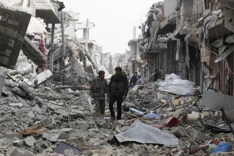 Fighters of the Kurdish People's Protection Units walk past damaged buildings in the northern Syrian town of Kobani, January 28, 2015. PHOTO BY REUTERS/Osman Orsal