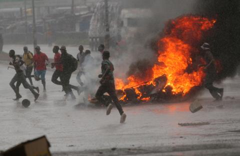People run at a protest as barricades burn during rainfall in Harare, Zimbabwe, January 14, 2019. PHOTO BY REUTERS/Philimon Bulawayo