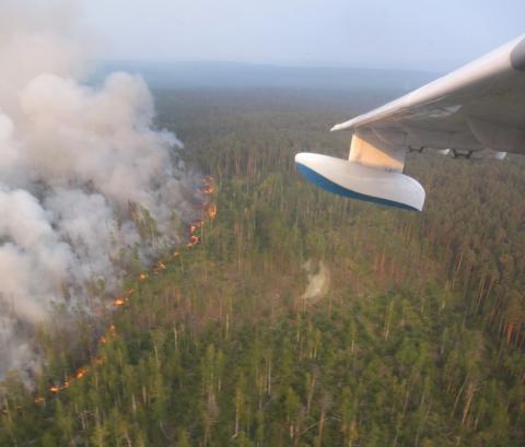 An aerial view through an aircraft window shows flame and smoke rising from a wildfire in Krasnoyarsk region, Russia in this handout picture obtained by Reuters on August 1, 2019. PHOTO BY REUTERS/Russian Emergencies Ministry in Krasnoyarsk region