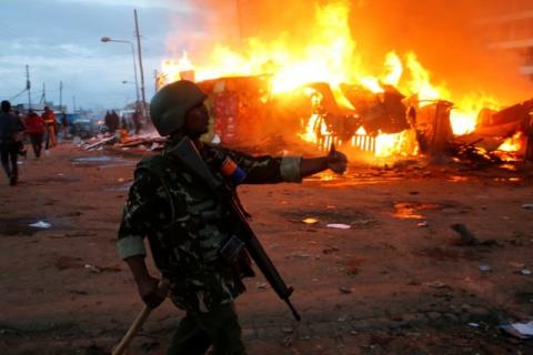 A riot policeman gestures near properties set on fire by rioters in Kawangware slums in Nairobi, Kenya, October 27, 2017. PHOTO BY REUTERS/Thomas Mukoya