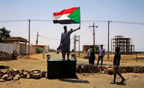 A Sudanese protester holds a national flag as he stands on a barricade along a street, demanding that the country's Transitional Military Council hand over power to civilians, in Khartoum, Sudan, June 5, 2019. PHOTO BY REUTERS/Stringer