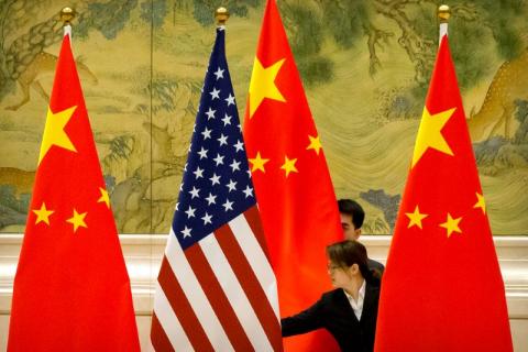 Chinese staffers adjust U.S. and Chinese flags before the opening session of trade negotiations between U.S. and Chinese trade representatives at the Diaoyutai State Guesthouse, Beijing, February 14, 2019. PHOTO BY REUTERS/Mark Schiefelbein/Pool 