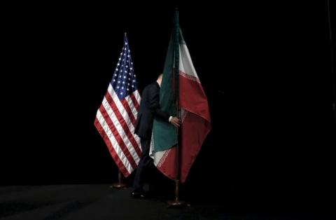 A staff member removes the Iranian flag from the stage during the Iran nuclear talks in Vienna, Austria, July 14, 2015. PHOTO BY REUTERS/Carlos Barria