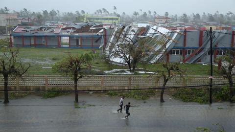 People walk down a flooded road next to buildings damaged by Cyclone Idai in Beira, Mozambique, March 17, 2019 in this still image taken from a social media video on March 18, 2019. PHOTO BY REUTERS/International Federation Of Red Cross And Red Crescent Societies