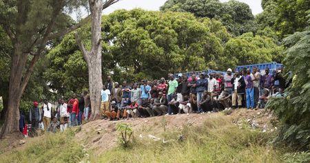 Foreigners look on as people board a bus for Zimbabwe from a camp for those affected by anti-immigrant violence in Chatsworth, north of Durban, April 19, 2015. PHOTO BY REUTERS/Rogan Ward