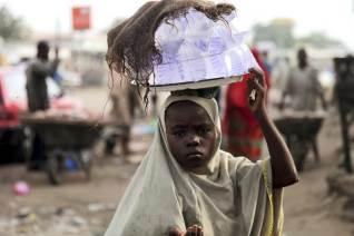 A girl hawks drinking water packed in sachets along a street after days of religious clashes in the northern Nigerian city of Maiduguri. PHOTO BY REUTERS/Akintunde Akinleye