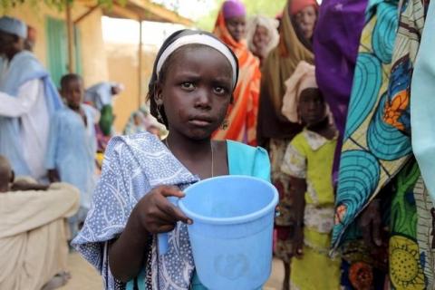 A girl drinks water as women queue for blankets and food given out by Nigerien soldiers in Damask, March 24, 2015. PHOTO BY REUTERS/Joe Penney