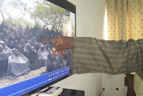 A man points to one of the girls abducted by Boko Haram on a screen showing a video of the captives, at the Government House in Maiduguri, Borno