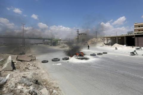 A gunman walking near burning tires as protesters block Damascus-Aleppo highway in the rebel-controlled area of Maaret al-Numan town in Idlib province, Syria, May 19, 2016. PHOTO BY REUTERS/Khalil Ashawi