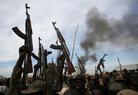 Rebel fighters hold up their rifles as they walk in front of a bushfire in a rebel-controlled territory in Upper Nile State, South Sudan, February 13, 2014. PHOTO BY REUTERS/Goran Tomasevic