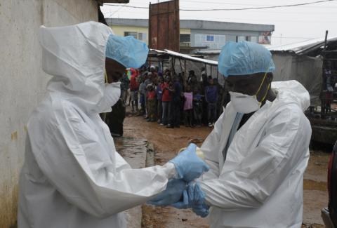 Health workers wear protective clothing before carrying an abandoned dead body presenting with Ebola symptoms at Duwala market in Monrovia