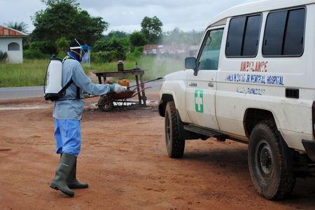 A health worker sprays disinfectant on an ambulance in Nedowein, Liberia, July 15, 2015. PHOTO BY REUTERS/James Giahyue