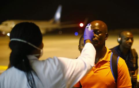 A health worker checks the temperature of a man arriving at Bata Airport, January 14, 2015. PHOTO BY REUTERS/Amr Abdallah Dalsh