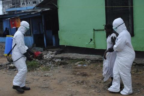 Health workers spray bleach solution on a woman suspected of having contracted the Ebola virus in Monrovia, Liberia