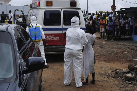 Health workers bring a woman suspected of having contracted Ebola virus to an ambulance in front of a crowd in Monrovia, Liberia