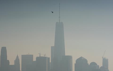 A helicopter flies over the Hudson River with One World Trade Center and Lower Manhattan in the background, on a hazy day in New York City, December 6, 2015. PHOTO BY REUTERS/Rickey Rogers