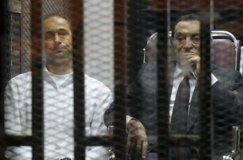 Egypt's ousted President Hosni Mubarak sits next to his son Gamal (L) inside a dock at the police academy on the outskirts of Cairo