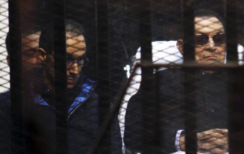 Former Egyptian President Hosni Mubarak listens next to his son Gamal (L) inside a dock during his trial at the police academy on the outskirts of Cairo, November 29, 2014. PHOTO BY REUTERS/Stringer