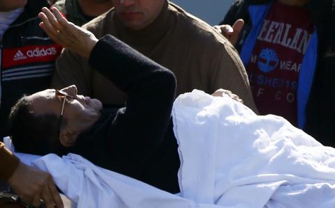 Former Egyptian President Hosni Mubarak waves to his supporters from his stretcher as he returns to Maadi military hospital in Cairo, November 29, 2014. PHOTO BY REUTERS/Amr Abdallah Dalsh