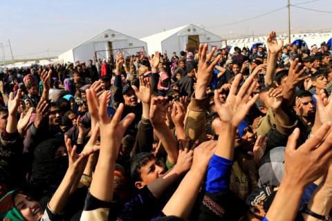 Displaced Iraqi people who fled from homes during a battle between Iraqi forces and Islamic State militants, receive bread at the Hammam al-Alil camp, south of Mosul, Iraq, March 14, 2017. PHOTO BY REUTERS/Thaier Al-Sudani