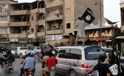 Members loyal to the Islamic State in Iraq and the Levant (ISIL) wave ISIL flags as they drive around Raqqa