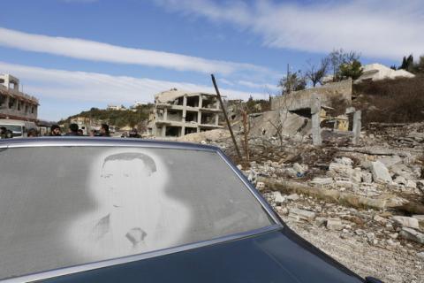 An image of Syria's President Bashar al-Assad is seen on a car parked in front of damaged buildings in the town of Rabiya, after pro-government forces recaptured the rebel-held town in coastal Latakia province, Syria January 27, 2016. PHOTO BY REUTERS/Omar Sanadiki