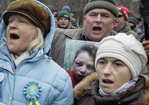 A protester holds a picture of journalist Tetyana Chornovil, who was beaten and left in a ditch just hours after publishing an article on the assets of top government officials, during a protest rally in front of the Ukrainian Ministry of Internal Affairs