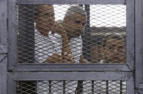 Al Jazeera journalists (L-R) Peter Greste, Mohammed Fahmy and Baher Mohamed stand behind bars at a court in Cairo