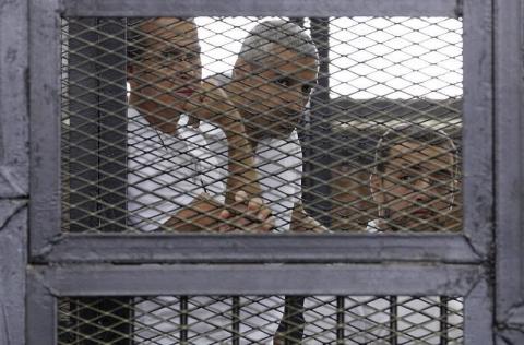 Al Jazeera journalists (L-R) Peter Greste, Mohammed Fahmy and Baher Mohamed stand behind bars at a court in Cairo