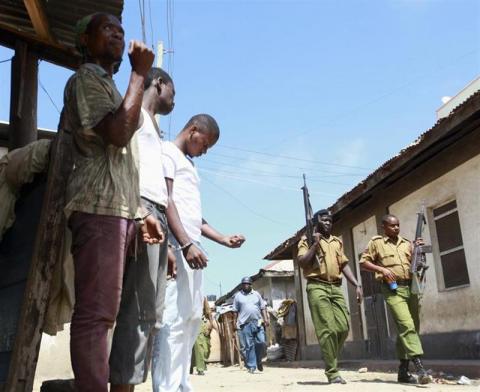 Kenyan administration policemen patrol the streets of Majengo past arrested youths after a protest of the killing of an Islamic cleric