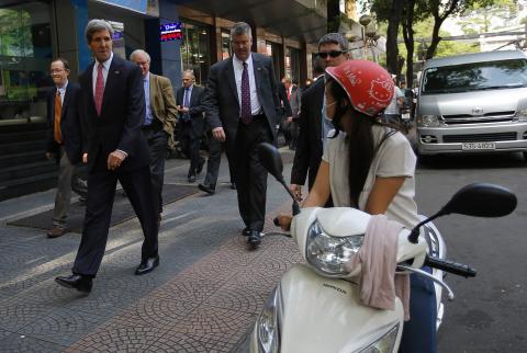 U.S. Secretary of State John Kerry (L) walks along a street in Ho Chi Minh City to attend a service at the Notre Dame Cathedral