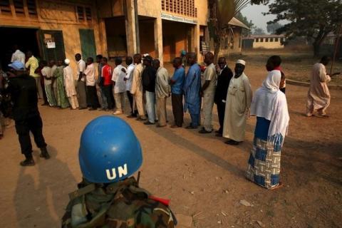 A United Nations security officer keeps guard as people wait in line to cast their votes during the second round of presidential and legislative elections in the mostly Muslim PK5 neighbourhood of Bangui, Central African Republic, February 14, 2016. PHOTO BY REUTERS/Siegfried Modola