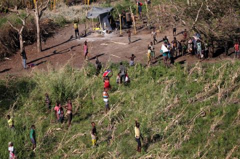 Locals look on as a chopper takes off after they received food aid from a South African National Defence Force (SANDF) helicopter in the aftermath of Cyclone Idai in Nhamatanda village, near Beira, Mozambique, March 26, 2019. PHOTO BY REUTERS/Siphiwe Sibeko