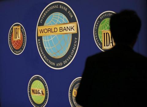 A man is silhouetted against the logo of the World Bank at the main venue for the International Monetary Fund (IMF) and World Bank annual meeting in Tokyo