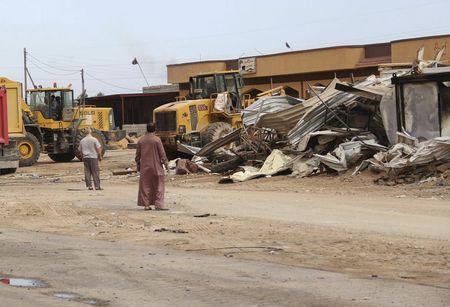 Men watch as bulldozers remove debris in front of a damaged building after a suicide car bomber blew himself up at a checkpoint in Dafniya outside Mistrata, Libya, May 31, 2015. PHOTO BY REUTERS/Stringer