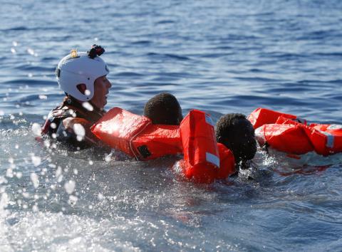 A rescue swimmer holds onto migrants frantically trying to stay afloat after falling off their rubber dinghy during a rescue operation by the Malta-based NGO Migrant Offshore Aid Station (MOAS) ship in the central Mediterranean in international waters some 15 nautical miles off the coast of Zawiya in Libya, April 14, 2017. PHOTO BY REUTERS/Darrin Zammit Lupi